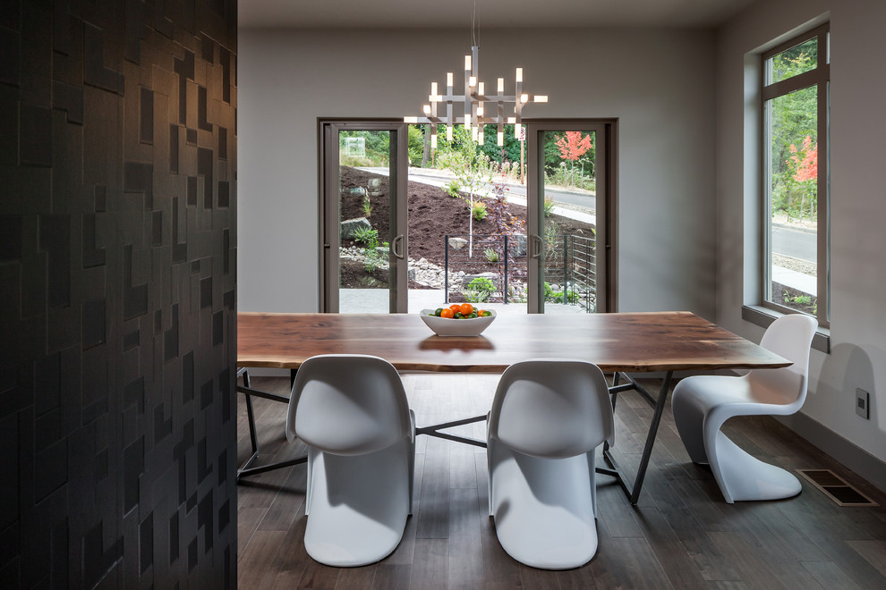 Réalisation d'une grande salle à manger ouverte sur le salon design avec un mur gris et un sol en bois brun.