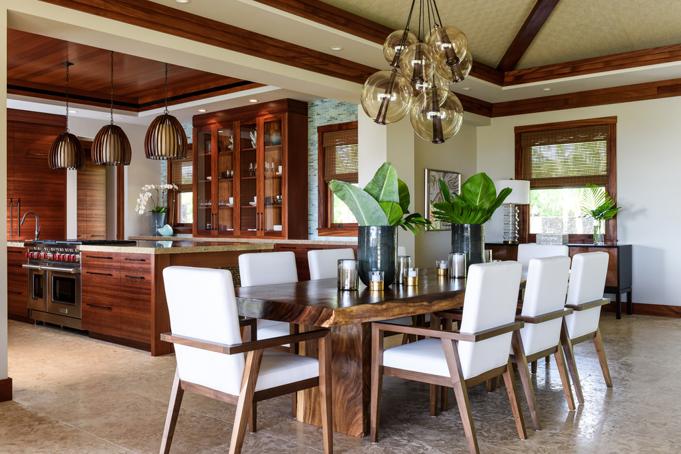 Large world-inspired open plan dining room in Hawaii with beige walls and limestone flooring.