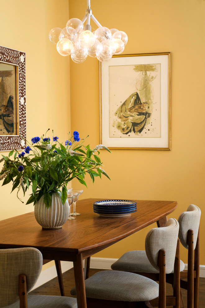 Idées déco pour une salle à manger rétro avec un mur jaune, un sol en bois brun et un sol marron.