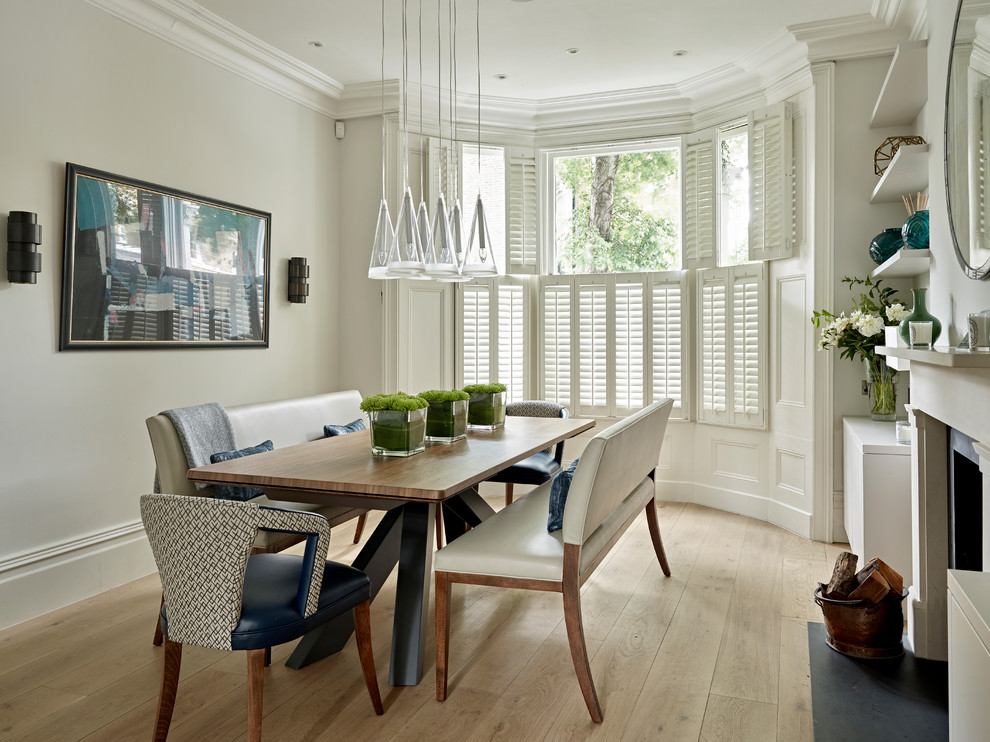 Design ideas for a medium sized traditional enclosed dining room in London with grey walls, light hardwood flooring, a wood burning stove, a stone fireplace surround and beige floors.