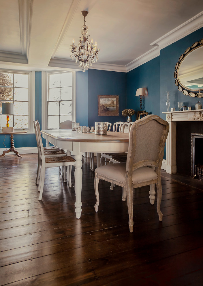 Aménagement d'une grande salle à manger classique fermée avec un mur bleu, parquet foncé, une cheminée standard et un manteau de cheminée en pierre.