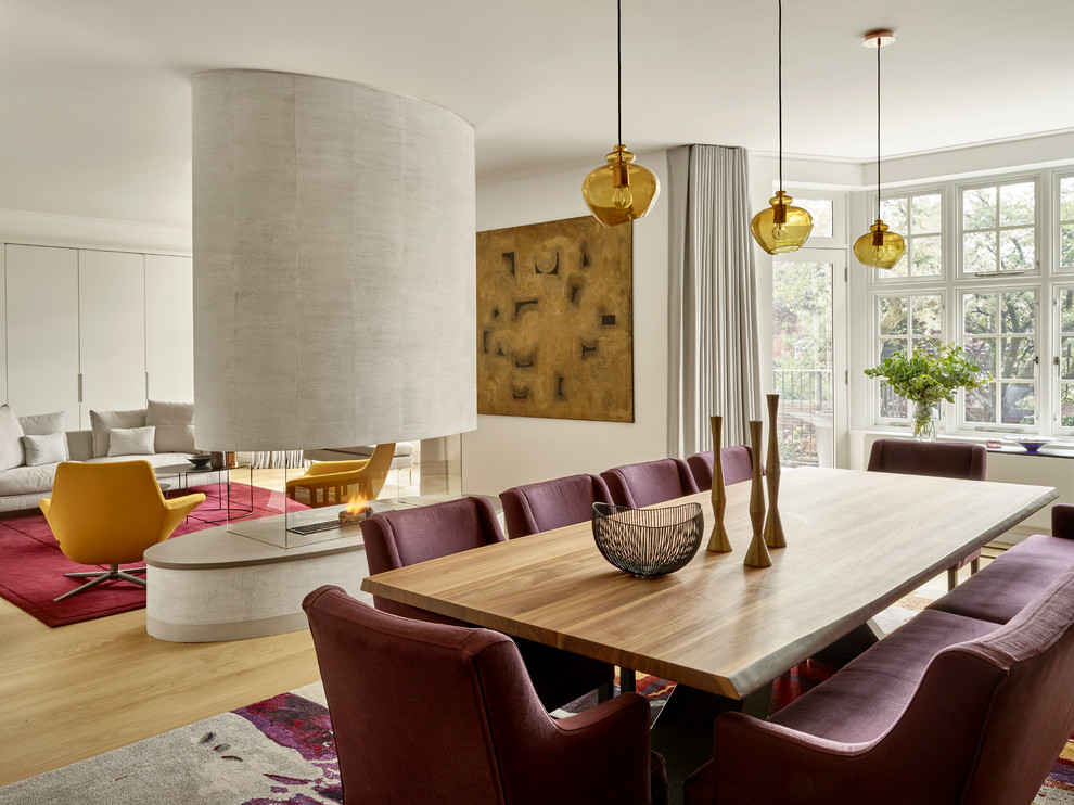 Пример оригинального дизайна: гостиная-столовая в современном стиле с светлым паркетным полом и двусторонним камином