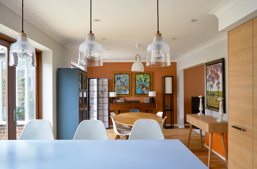 На фото: кухня-столовая в стиле неоклассика (современная классика) с оранжевыми стенами, паркетным полом среднего тона и коричневым полом
