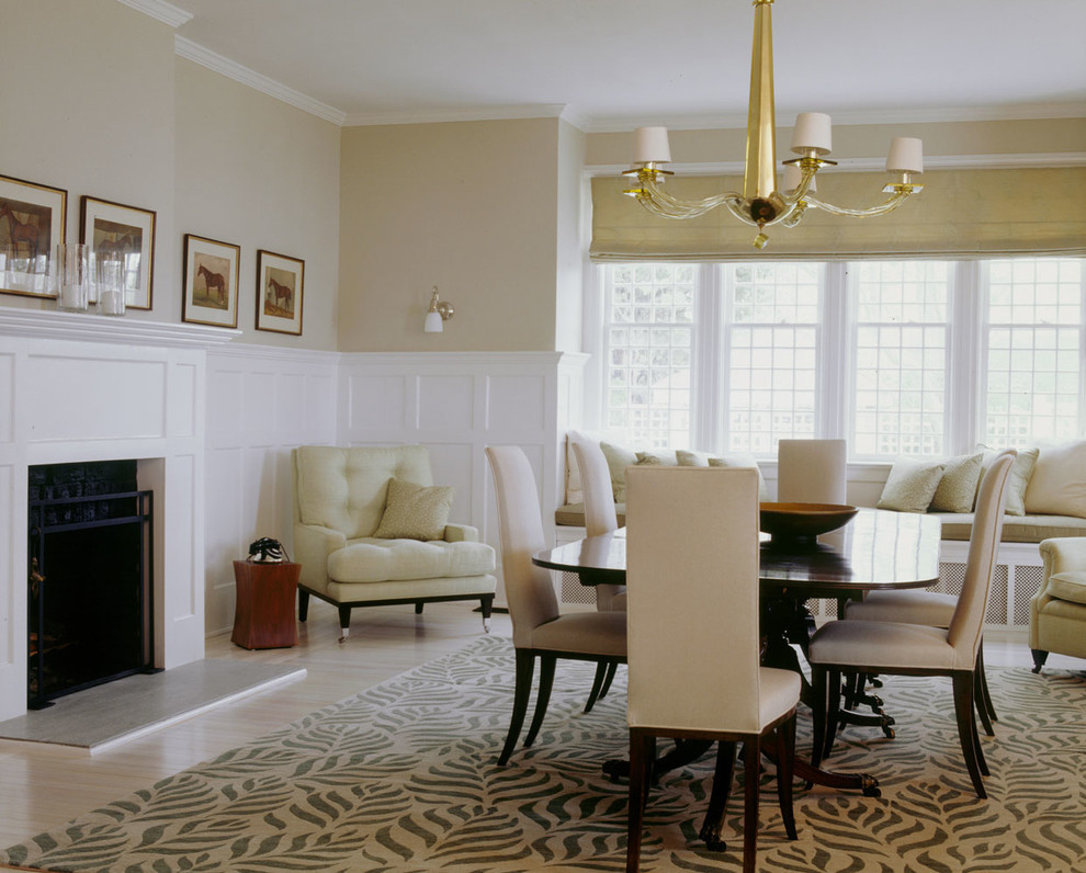 Esempio di una sala da pranzo aperta verso il soggiorno minimal di medie dimensioni con pareti beige, parquet chiaro, camino classico e cornice del camino in cemento