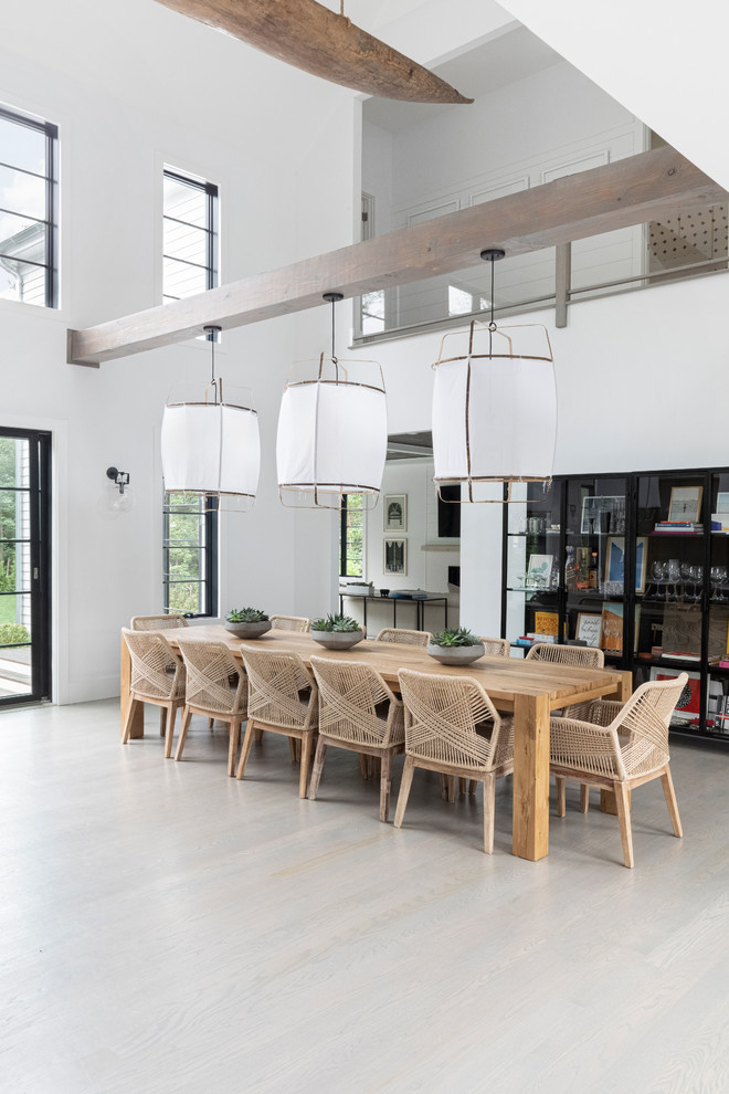 Exemple d'une salle à manger ouverte sur la cuisine bord de mer de taille moyenne avec un mur blanc, parquet foncé et un sol gris.