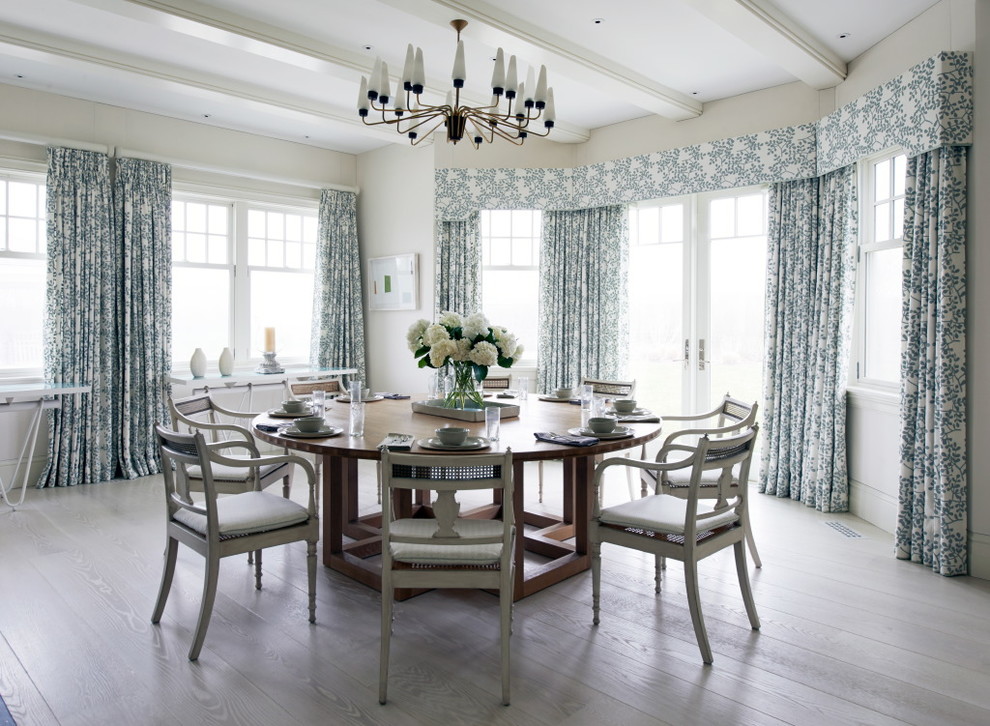This is an example of a beach style dining room in New York with beige walls and light hardwood flooring.