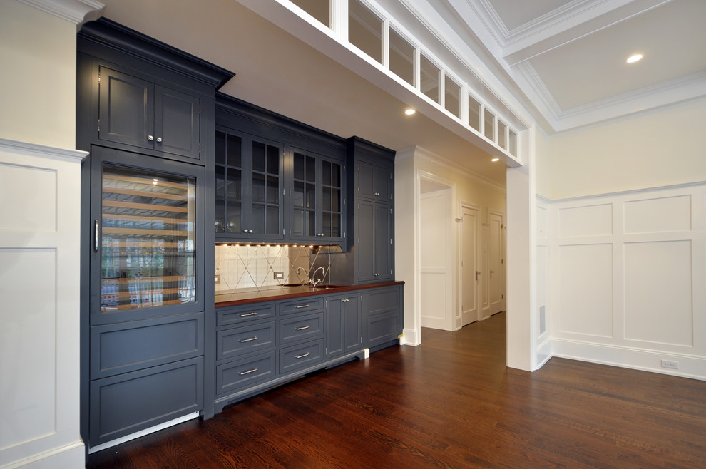 Foto di un'ampia sala da pranzo aperta verso la cucina classica con pareti bianche, parquet scuro, pavimento marrone, soffitto ribassato e pannellatura
