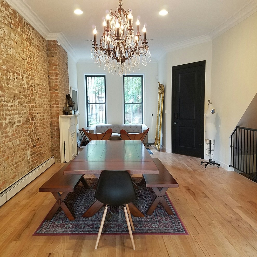 This is an example of a large scandinavian open plan dining room in New York with light hardwood flooring, a standard fireplace and a wooden fireplace surround.
