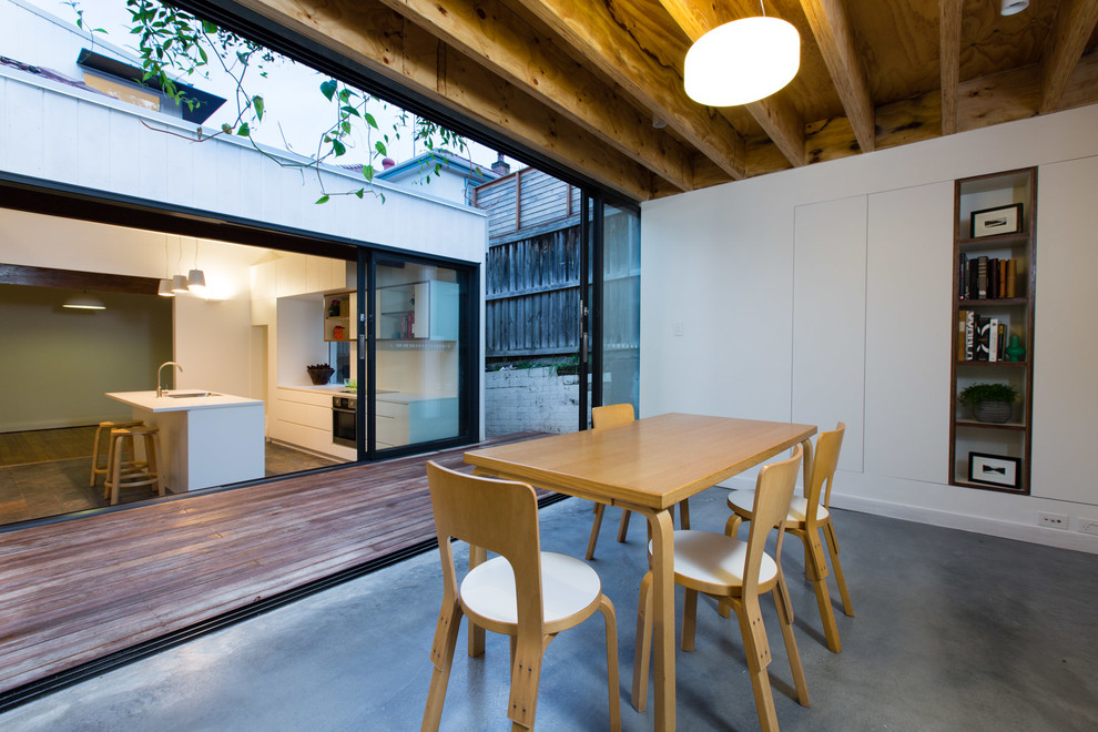 Immagine di una sala da pranzo design di medie dimensioni con pareti bianche, pavimento in cemento e pavimento grigio