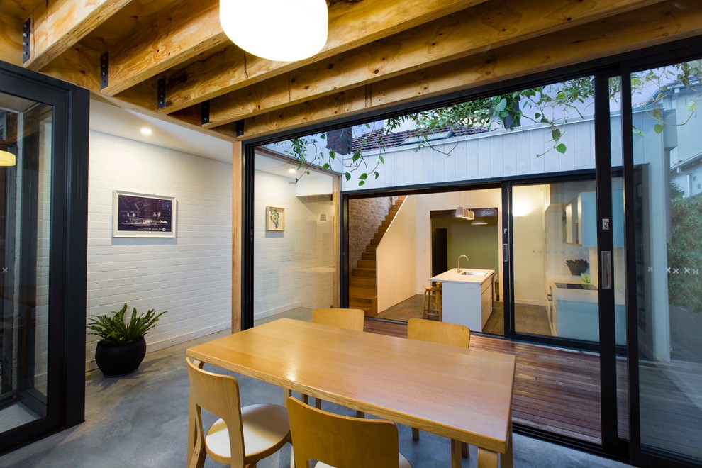 Ispirazione per una sala da pranzo design di medie dimensioni con pareti bianche, pavimento in cemento e pavimento grigio