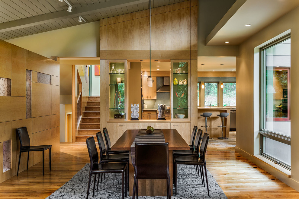 Inspiration pour une salle à manger design avec un sol en bois brun et un mur beige.