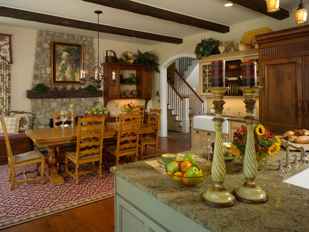 Cette photo montre une salle à manger ouverte sur la cuisine nature de taille moyenne avec un mur beige, un sol en bois brun, une cheminée standard, un manteau de cheminée en pierre et un sol marron.