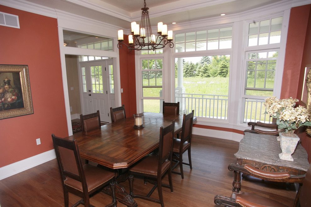 Aménagement d'une salle à manger classique fermée et de taille moyenne avec un mur rouge et un sol en bois brun.