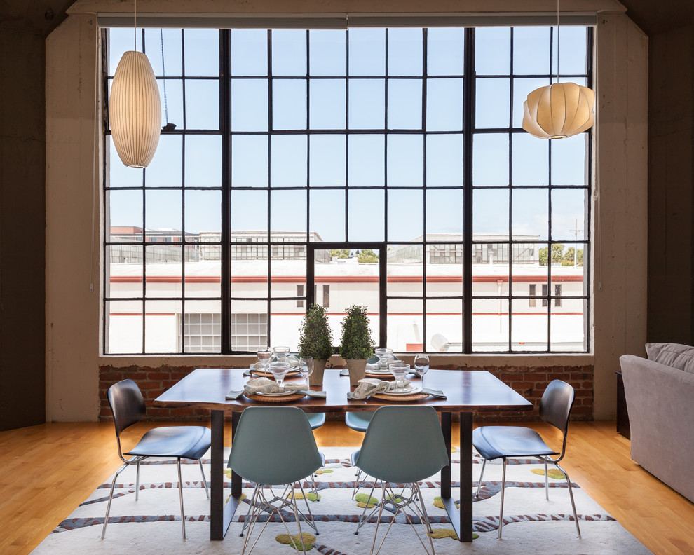 Foto di una sala da pranzo aperta verso il soggiorno industriale con pavimento in legno massello medio