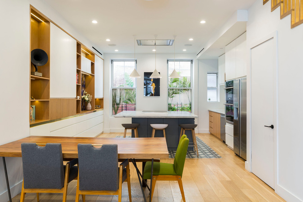 Immagine di una grande sala da pranzo aperta verso la cucina design con pareti bianche, parquet chiaro e pavimento beige