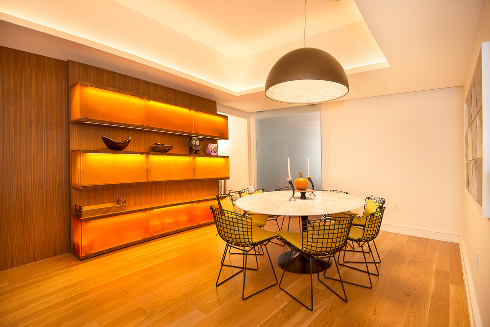 Réalisation d'une salle à manger design fermée avec un mur blanc et un sol en bois brun.