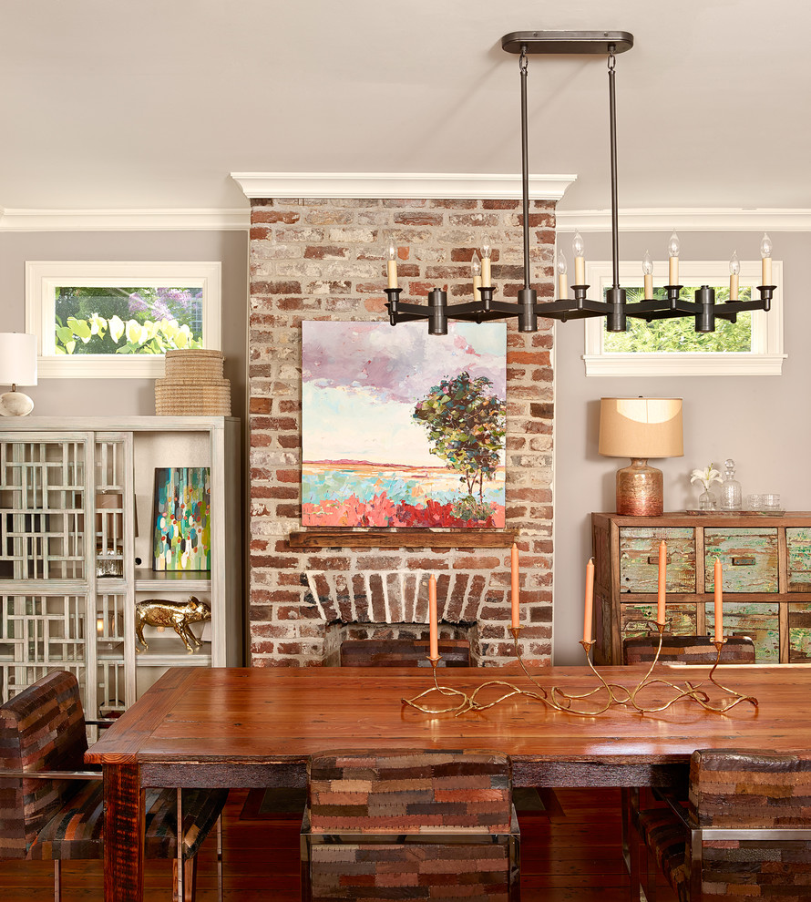 Immagine di una sala da pranzo aperta verso la cucina tradizionale di medie dimensioni con pareti grigie, pavimento in legno massello medio, cornice del camino in mattoni, camino classico e pavimento marrone