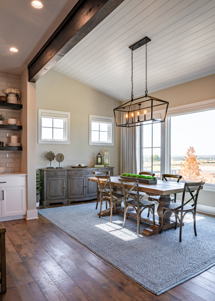 Cette image montre une grande salle à manger ouverte sur la cuisine rustique avec un mur gris, un sol en bois brun et un plafond en lambris de bois.
