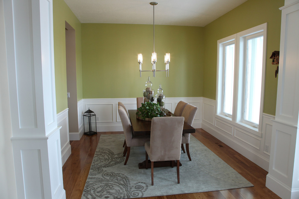 Aménagement d'une salle à manger ouverte sur le salon classique de taille moyenne avec un mur vert, un sol en bois brun et aucune cheminée.