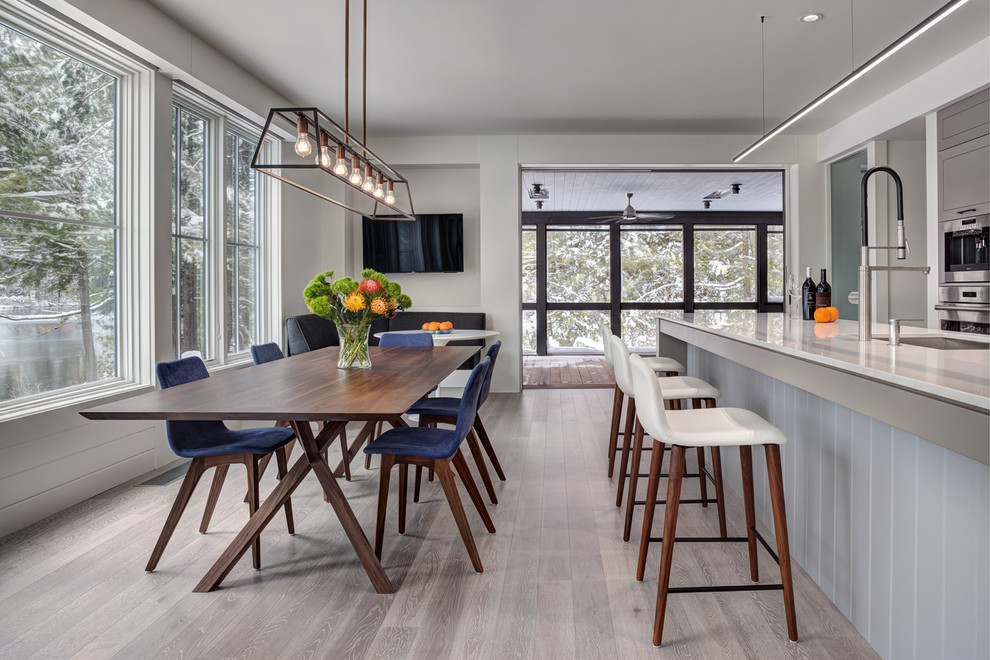 Cette photo montre une salle à manger ouverte sur la cuisine tendance de taille moyenne avec parquet clair, un sol gris et un mur gris.