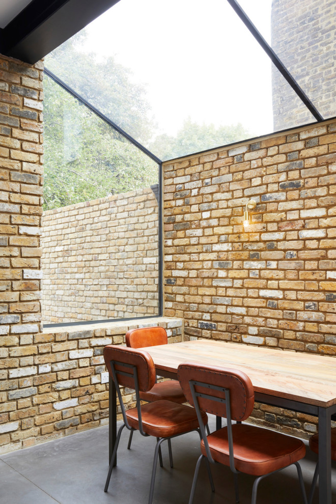 Réalisation d'une petite salle à manger design fermée avec un mur orange, sol en béton ciré et un sol gris.