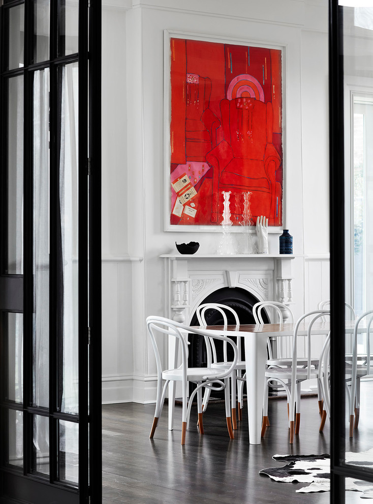 Cette image montre une grande salle à manger design avec un mur blanc, parquet foncé, une cheminée standard et un sol marron.