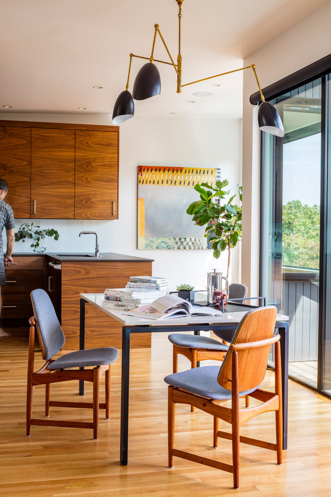 Cette photo montre une salle à manger ouverte sur la cuisine rétro avec parquet clair et un sol marron.