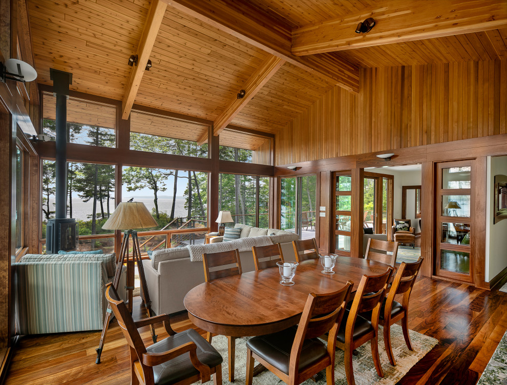 Exemple d'une grande salle à manger ouverte sur le salon tendance avec un sol en bois brun, une cheminée d'angle et un manteau de cheminée en métal.
