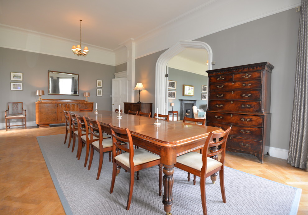 Immagine di una sala da pranzo chic chiusa e di medie dimensioni con pareti grigie, parquet chiaro e pavimento marrone