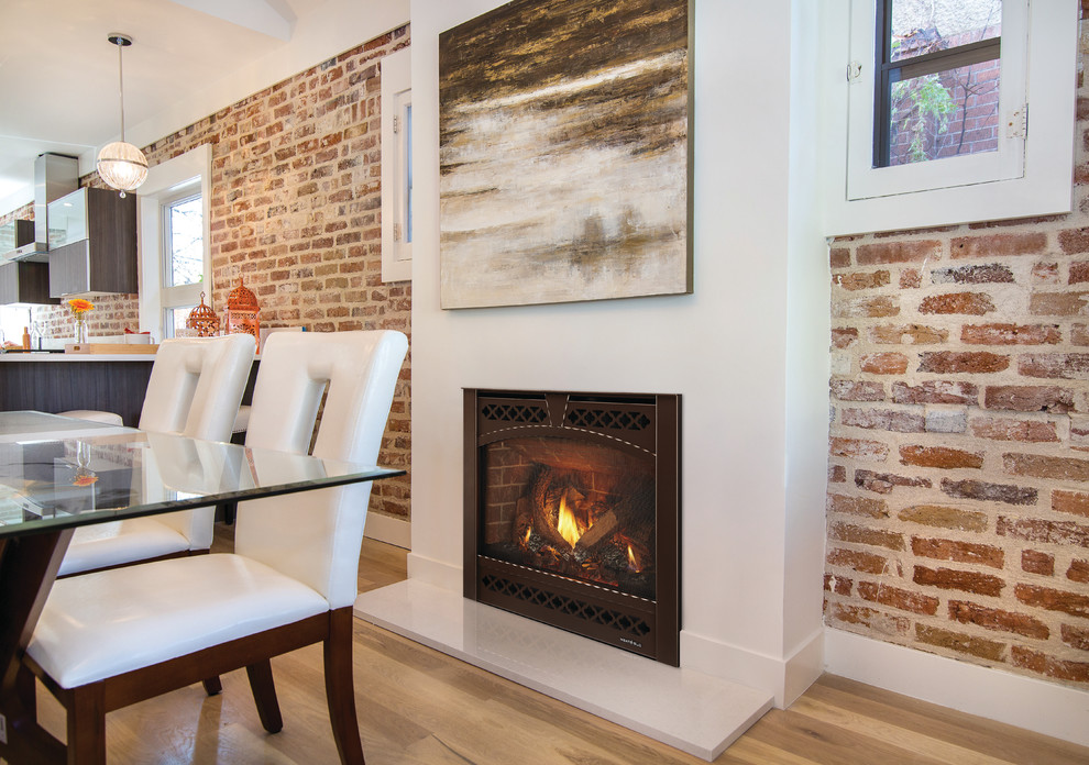 Inspiration pour une salle à manger ouverte sur la cuisine design de taille moyenne avec un mur rouge, parquet clair, une cheminée standard, un manteau de cheminée en bois et un sol beige.