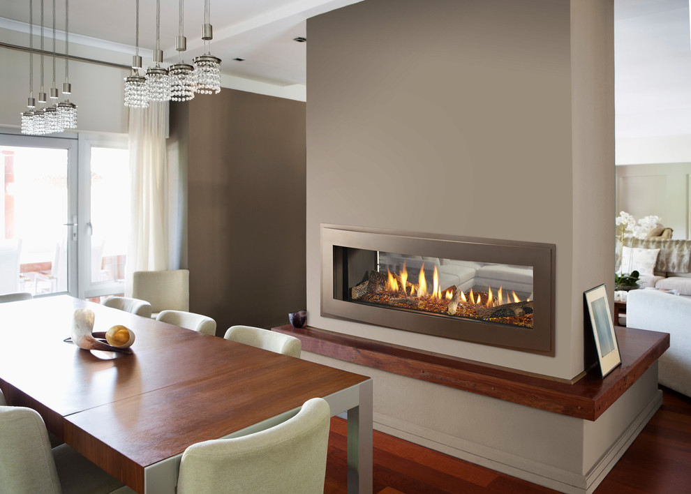 Idée de décoration pour une salle à manger ouverte sur le salon minimaliste de taille moyenne avec un mur marron, un sol en bois brun, une cheminée double-face, un manteau de cheminée en métal et un sol marron.