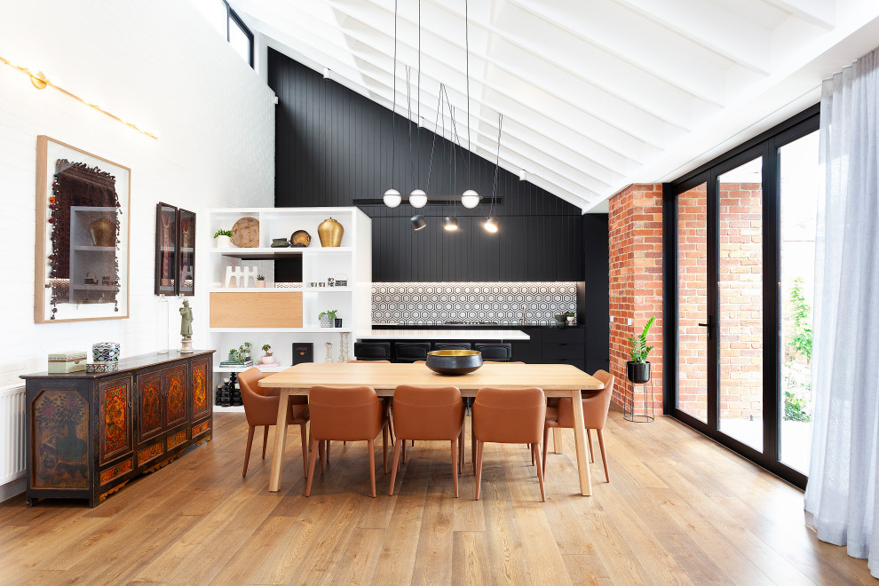 Esempio di una sala da pranzo aperta verso la cucina minimal con pareti bianche, pavimento in legno massello medio, pavimento marrone, travi a vista, soffitto a volta e pannellatura