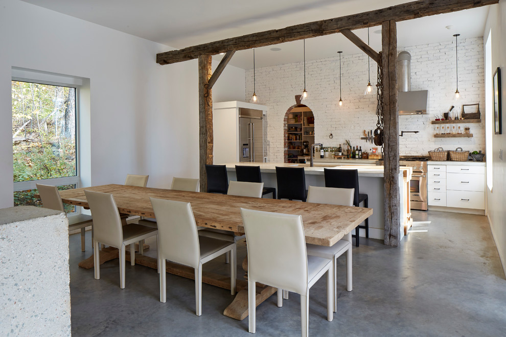 Esempio di una sala da pranzo aperta verso la cucina country con pavimento in cemento