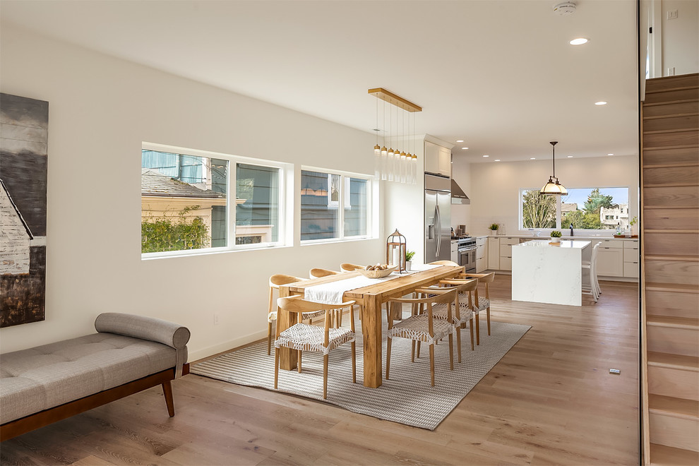 Idées déco pour une salle à manger ouverte sur le salon contemporaine avec un mur blanc, un sol en bois brun et un sol marron.