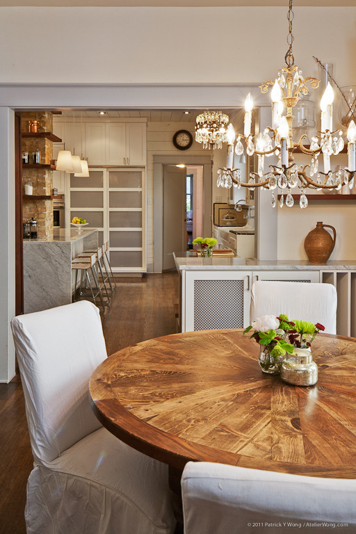 Aménagement d'une salle à manger ouverte sur la cuisine campagne avec un mur blanc et un sol en bois brun.