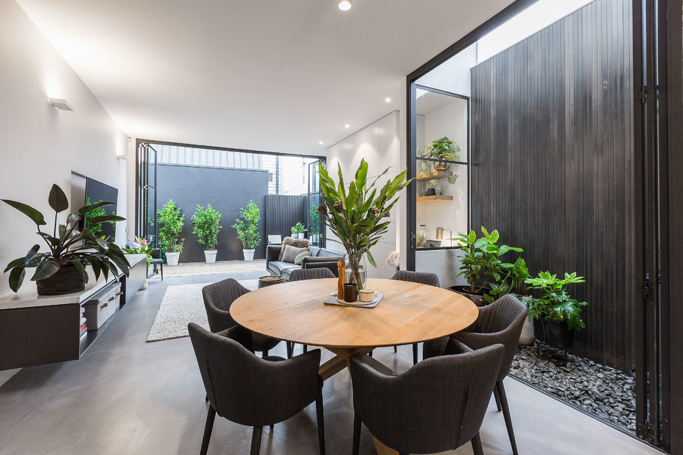 Photo of a small contemporary open plan dining room in Melbourne with white walls, concrete flooring and grey floors.