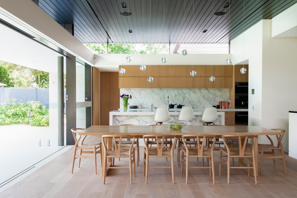Modelo de comedor contemporáneo abierto con paredes blancas y suelo de madera en tonos medios