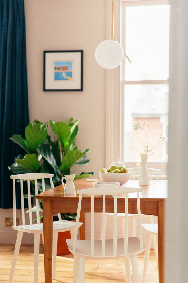 Immagine di una sala da pranzo aperta verso il soggiorno moderna di medie dimensioni con parquet chiaro e pareti rosa