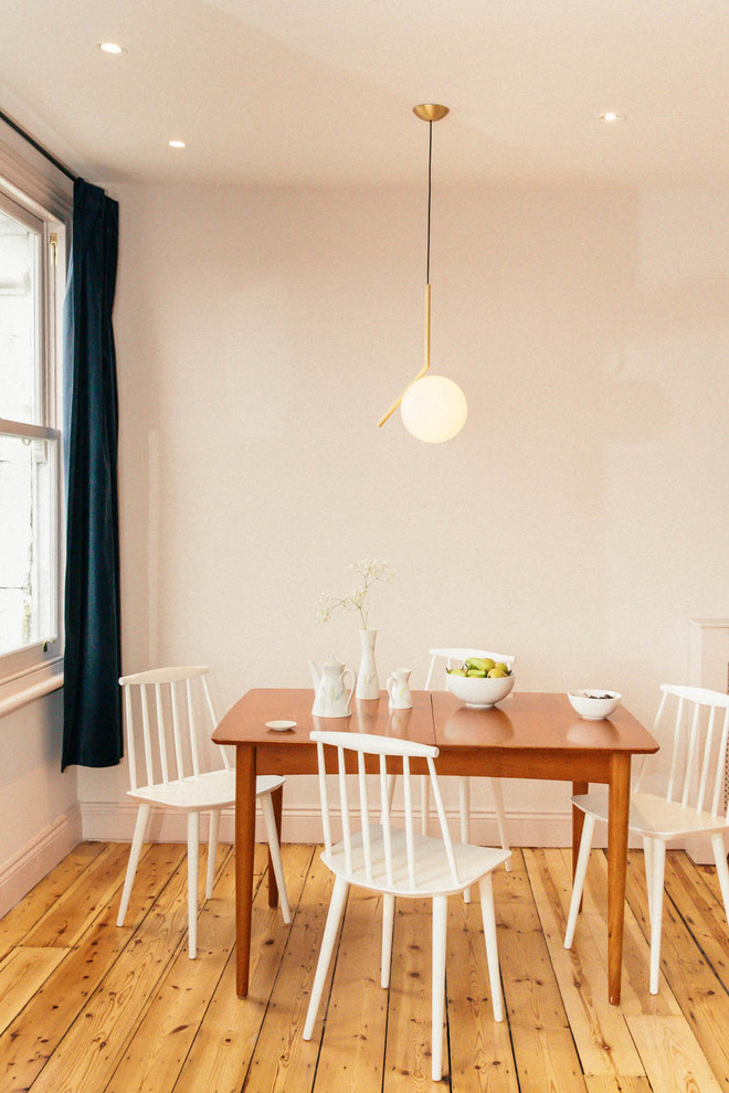 Foto de comedor retro de tamaño medio abierto con suelo de madera clara y paredes rosas