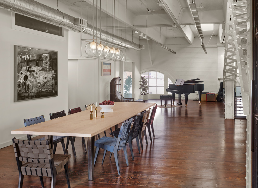 Photo of an industrial dining room in San Francisco with white walls and dark hardwood flooring.