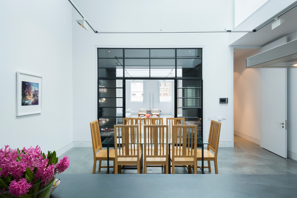 Expansive urban kitchen/dining room in London with white walls and concrete flooring.