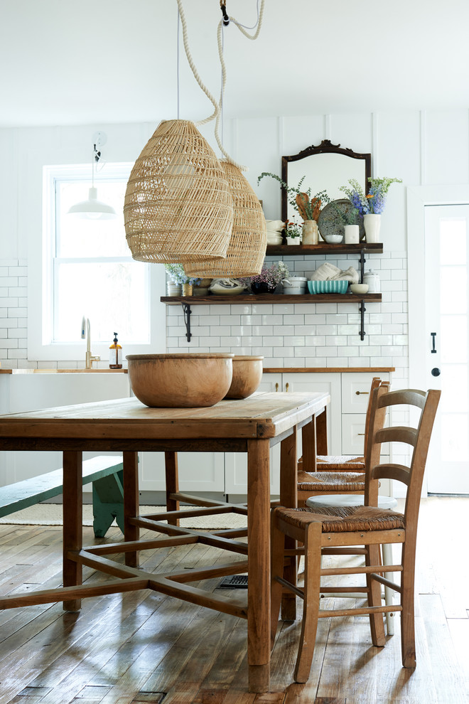 Example of a mid-sized cottage medium tone wood floor and brown floor kitchen/dining room combo design in Other with white walls