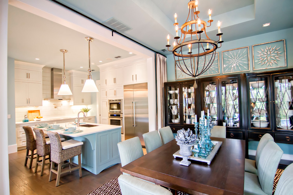 Immagine di una grande sala da pranzo aperta verso la cucina tropicale con pareti blu, pavimento in legno massello medio, nessun camino e pavimento marrone