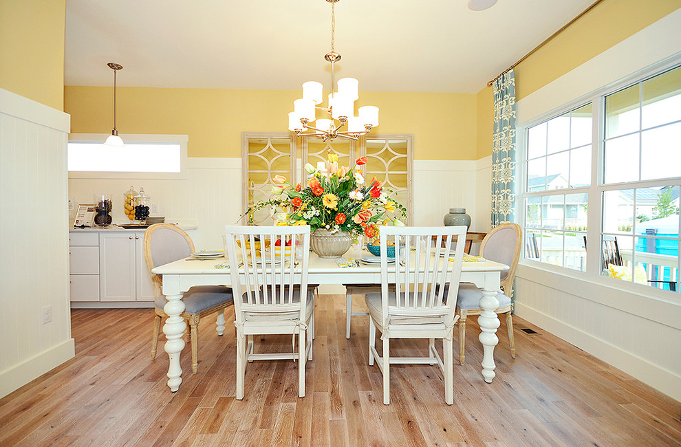 Aménagement d'une salle à manger classique avec un mur jaune et un sol en bois brun.