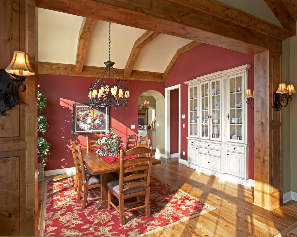 Idées déco pour une salle à manger classique fermée et de taille moyenne avec un mur rouge, un sol en bois brun, aucune cheminée et un sol marron.