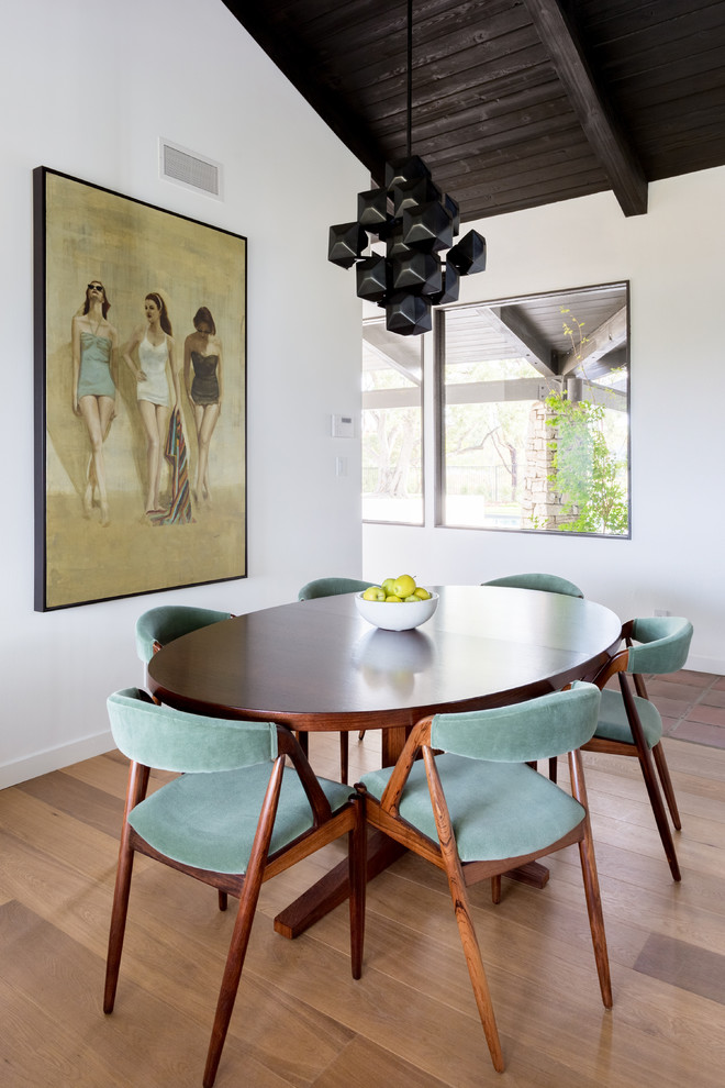 Cette image montre une salle à manger vintage avec un mur blanc, un sol en bois brun et un sol marron.