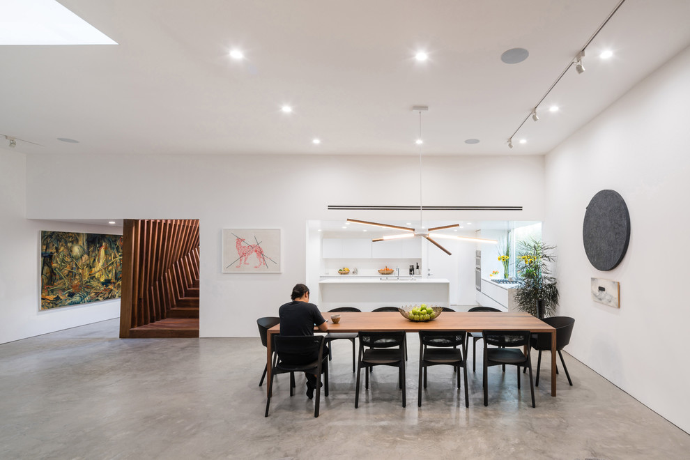 Offenes Modernes Esszimmer mit weißer Wandfarbe, Betonboden und grauem Boden in Los Angeles