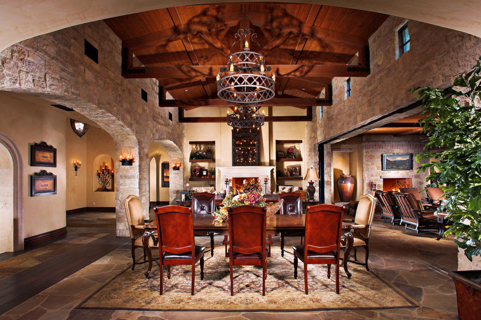 This is an example of a medium sized mediterranean open plan dining room in Los Angeles with grey walls, slate flooring, a standard fireplace and a stone fireplace surround.