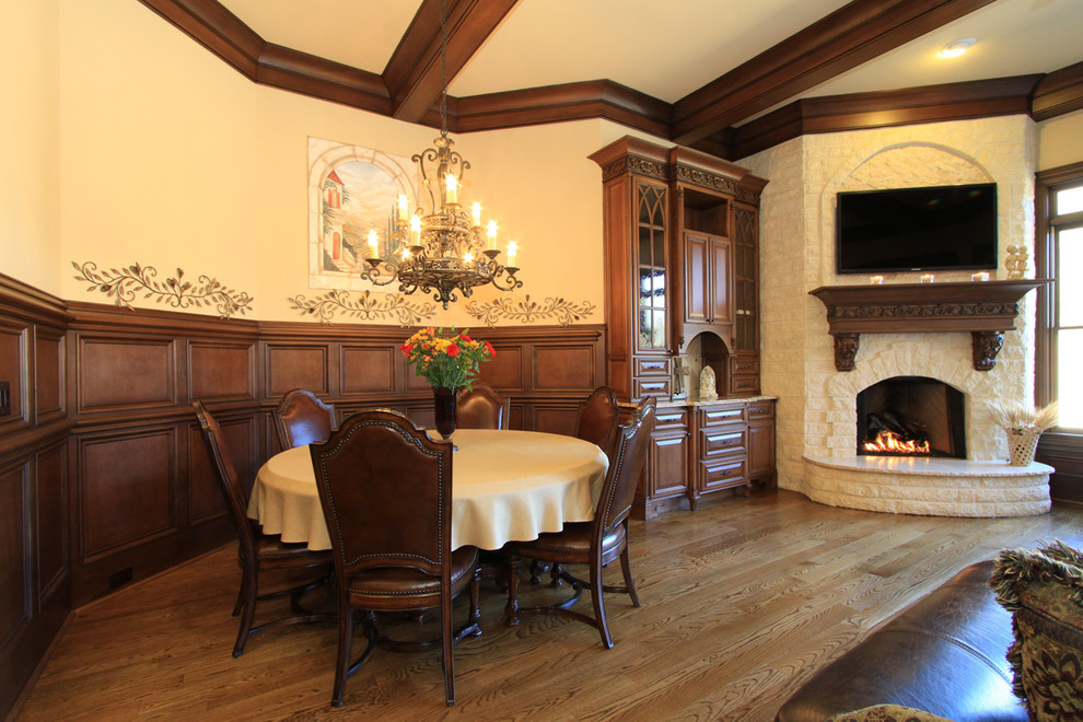 Foto di un'ampia sala da pranzo classica con pareti beige, pavimento in legno massello medio, camino ad angolo e cornice del camino in pietra