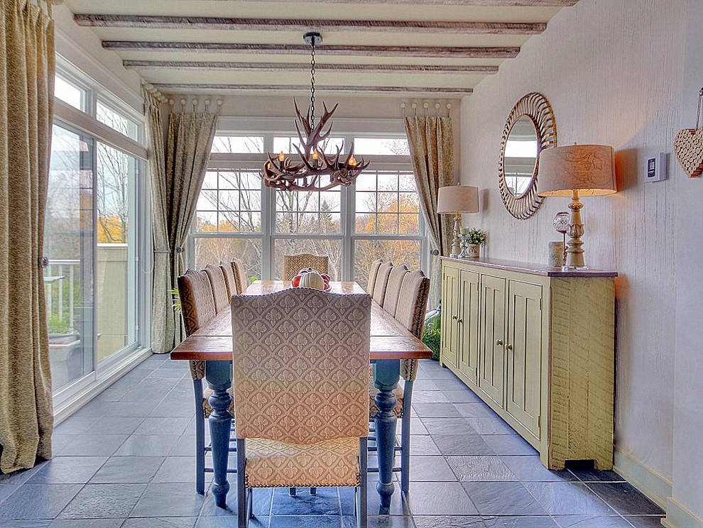 This is an example of a medium sized farmhouse dining room in Montreal with white walls and slate flooring.